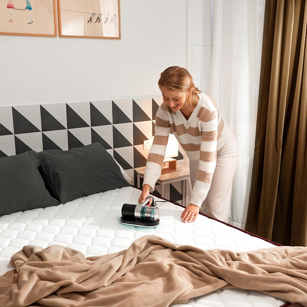 Aspirator antiacarieni pentru saltele si lenjerii de pat Cecotec, Conga Rockstar 3000, sterilizare cu lumina UV-C, dezinfectare in profunzime cu aer cald, elimina pana la 99,9% din bacterii, 10 kPa, cyclonic system, negru/argintiu, femeie care curata o saltea